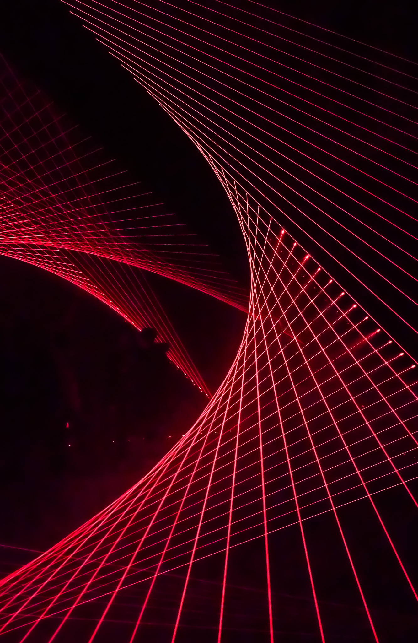 Red laser lines forming a twisting spiral in the dark
